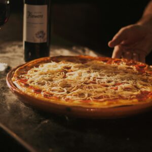 Delicious pepperoni pizza paired with red wine, showcasing a rustic dining experience in Centro, RJ.