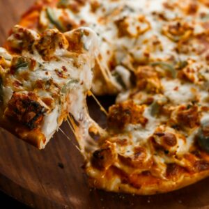 Mouth-watering pepperoni pizza slice with melted cheese on a wooden board.